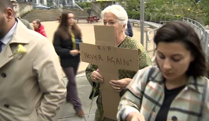 Una mujer porta una cruz en la que se puede leer 'RIP never again' durante la manifestación en Bruselas.