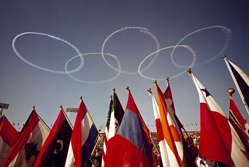 Banderas de varias naciones y los anillos olímpicos en el cielo se ven en el Estadio Olímpico de Tokio, Japón, el 10 de octubre de 1964.