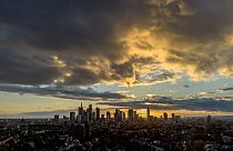 The sun sets behind the skyline as clouds drift by in Frankfurt, Germany, Tuesday, Nov. 7, 2023
