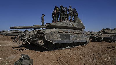 Israeli soldiers work on armored military vehicles at a staging ground near the Israeli-Gaza border, in southern Israel, Wednesday, May 8, 2024. 