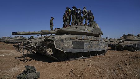 Israeli soldiers work on armored military vehicles at a staging ground near the Israeli-Gaza border, in southern Israel, Wednesday, May 8, 2024. 
