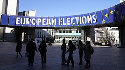 Un gruppo si trova sotto uno striscione elettorale fuori dal Parlamento europeo a Bruxelles il 29 aprile 2024. 