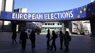 Μια ομάδα στέκεται κάτω από ένα προεκλογικό πανό έξω από το Ευρωπαϊκό Κοινοβούλιο στις Βρυξέλλες στις 29 Απριλίου 2024. 