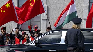 People wave Chinese and Hungarian flags for the Chinese President Xi Jinping outside the Buda Castle in Budapest, 9 May 2024