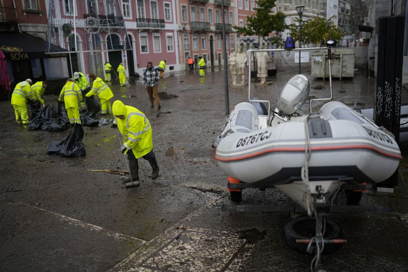 Municipal workers clean a street that was flooded overnight in Alges, just outside Lisbon, December 2022