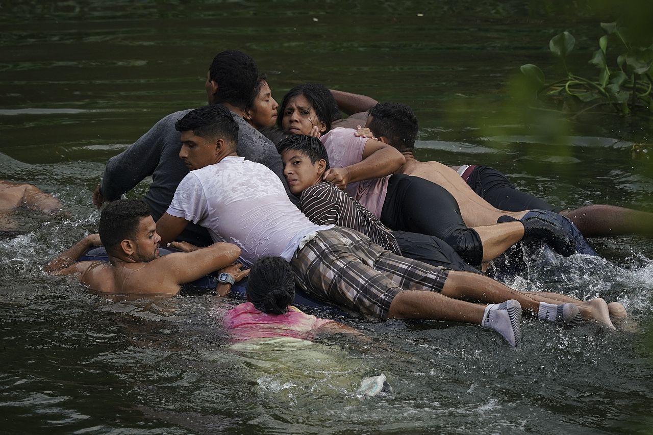 Migrants cross the Rio Bravo on an inflatable mattress into the United States from Matamoros, Mexico