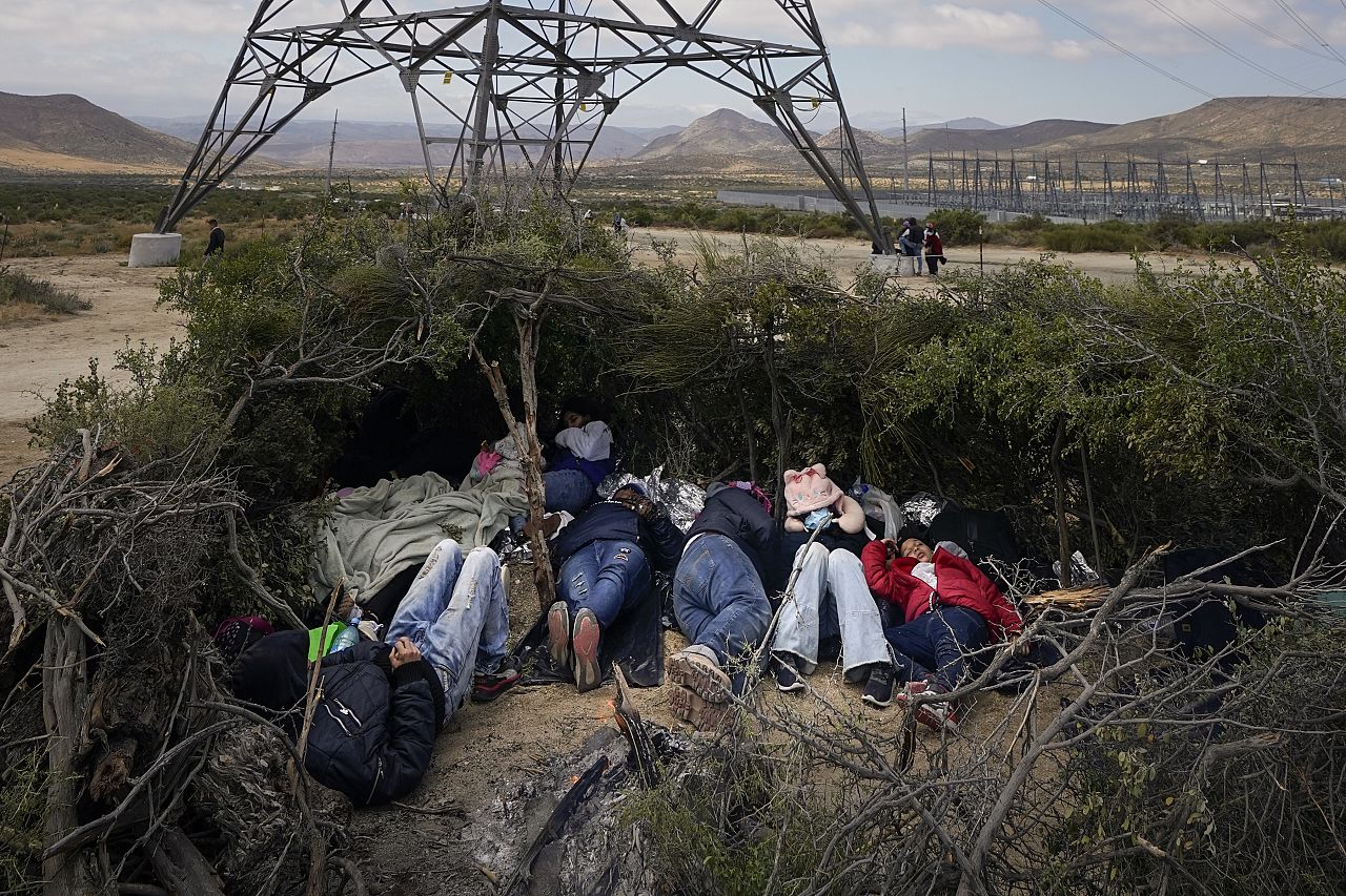 A group of migrants sleep in a makeshift campsite as they wait to apply for asylum after crossing the US border, near Jacumba, California