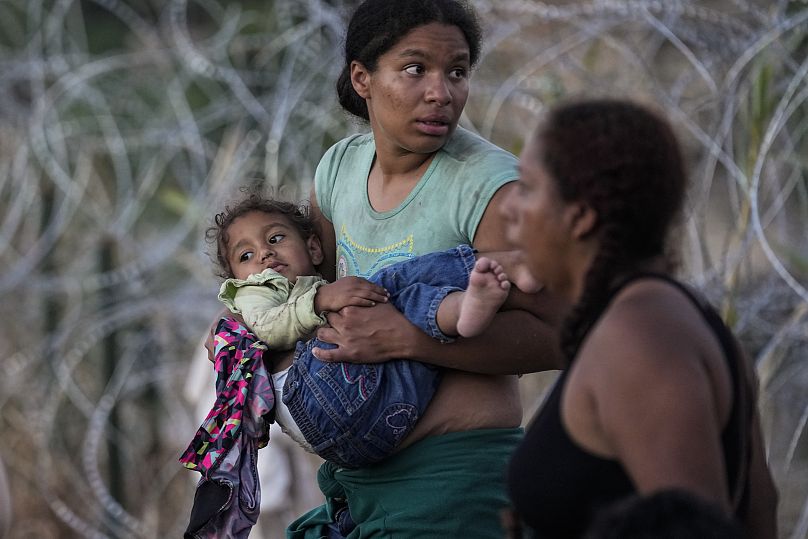 Una mujer lleva a su hijo en brazos después de que ella y otros inmigrantes cruzaran el Río Grande y entraran en Estados unidos desde México, en Eagle Pass, Texas.