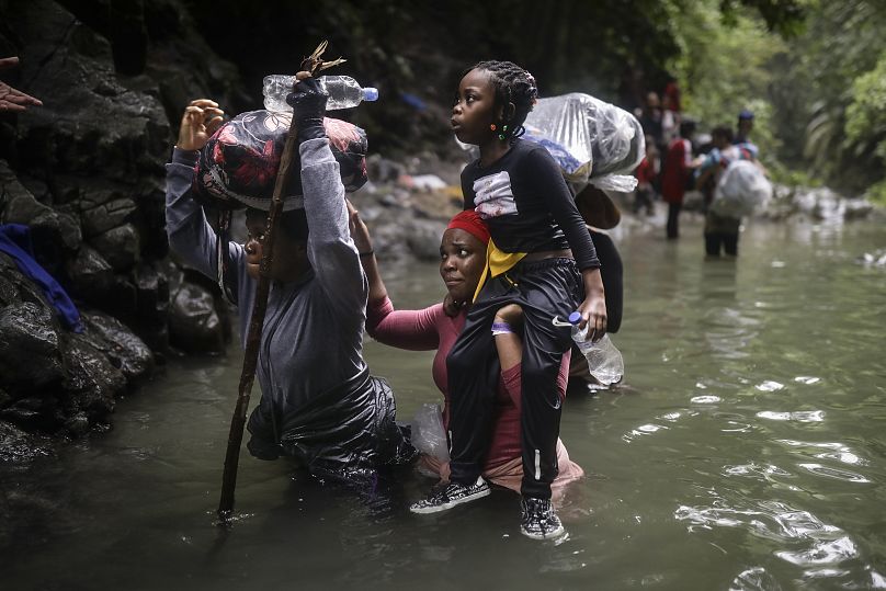 Inmigrantes haitianos vadean el agua mientras cruzan el Paso del Darién, de Colombia a Panamá, con la esperanza de llegar a Estados Unidos.