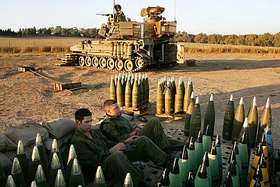 Nahal Oz yerleşim birimi yakınlarındaki bir mevzide seyyar bir topçu silahının yanında mermiler arasında dinlenen İsrail askerleri (arşiv)