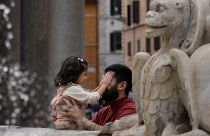 رجل يداعب ابنته بالقرب من نافورة في العاصمة الإيطالية روما