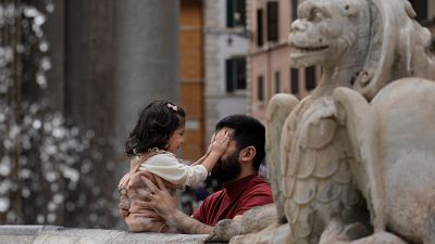 رجل يداعب ابنته بالقرب من نافورة في العاصمة الإيطالية روما