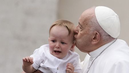 Pope Francis kisses a child at the end of his weekly general audience in St. Peter's Square, at the Vatican, Wednesday, May 8, 2024
