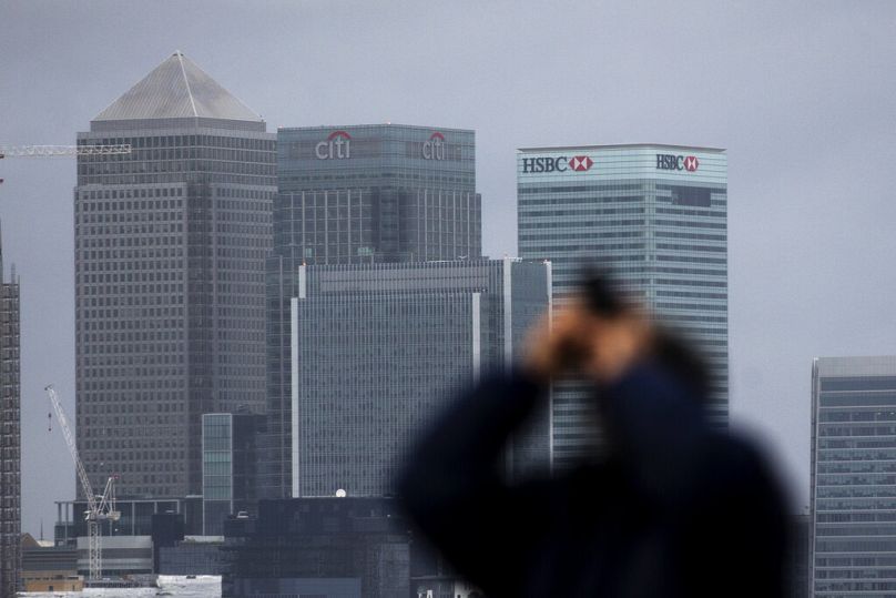 a tourist takes a picture backdropped by the HSBC headquarters building in London, February 2016