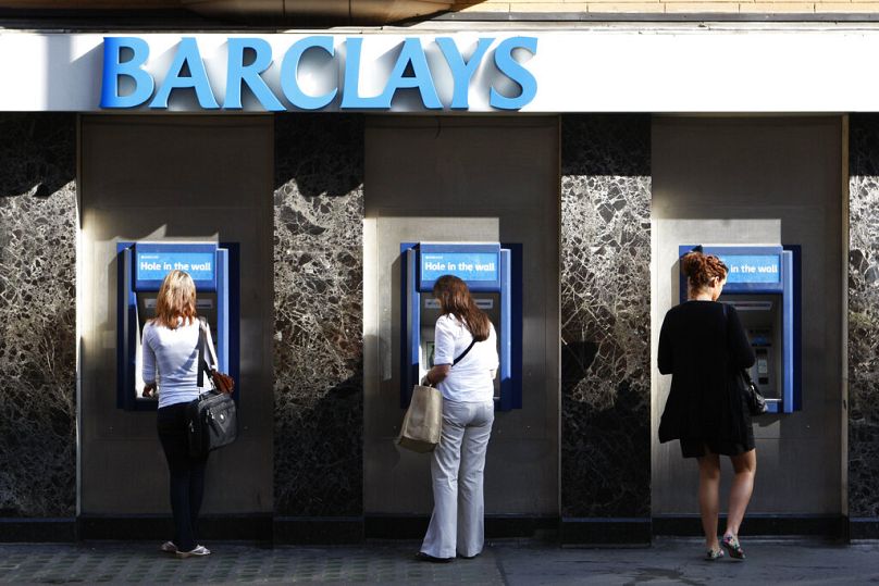 People use the cash machines at a branch of Barclays Bank in central London, August 2009