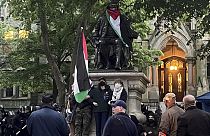 متظاهرون يتشبثون بأذرعهم عند تمثال بن فرانكلين في حرم جامعة بنسلفانيا