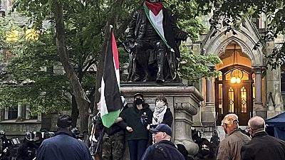 متظاهرون يتشبثون بأذرعهم عند تمثال بن فرانكلين في حرم جامعة بنسلفانيا