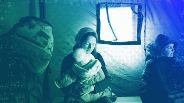 A refugee fleeing the conflict from neighbouring Ukraine holds her baby as she sits in a tent at the Romanian-Ukrainian border, in Siret, February 2022