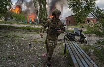 Ukrainischer Polizist vor einem brennendes Haus, das durch einen russischen Luftangriff in Wowtschansk zerstört wurde. 11. Mai 2024