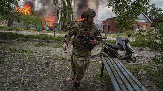 Ukrainischer Polizist vor einem brennendes Haus, das durch einen russischen Luftangriff in Wowtschansk zerstört wurde. 11. Mai 2024