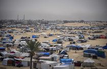 Les Palestiniens déplacés par l'offensive aérienne et terrestre israélienne sur la bande de Gaza marchent dans un camp de tentes de fortune à Rafah, le 10 mai 2024.
