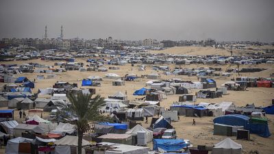 Les Palestiniens déplacés par l'offensive aérienne et terrestre israélienne sur la bande de Gaza marchent dans un camp de tentes de fortune à Rafah, le 10 mai 2024.