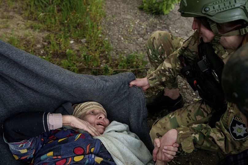 A police officer speaks to en elderly woman after a Russian airstrike during evacuation in Vovchansk, Ukraine