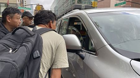 مهاجرون صينيون يتحدثون إلى صاحب سيارة بشان العمل في حضائر بناء في نيويورك. 2024/05/03
