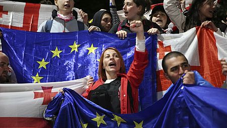 Manifestantes seguram bandeiras da Geórgia e da UE durante protestos à porta do parlamento