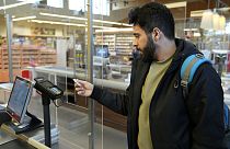 Un hombre refugiado usa una tarjeta para pagar en un supermercado.