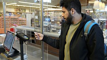 Un hombre refugiado usa una tarjeta para pagar en un supermercado.