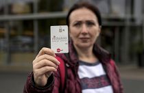 Erdina Laca, a 45-year-old asylum seeker, shows her special payment card in front of a grocery store, in Eichsfeld, Germany, Wednesday, April 24, 2024. 