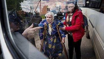 Menschen helfen Liudmila, 85, nach ihrer Evakuierung aus Wovtschansk, Ukraine, am Sonntag, 12. Mai 2024, in einen Bus zu steigen. 