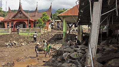 أشخاص يتفقدون المباني المتضررة من الفيضانات المفاجئة في أجام، غرب سومطرة، إندونيسيا، 13 مايو 2024.