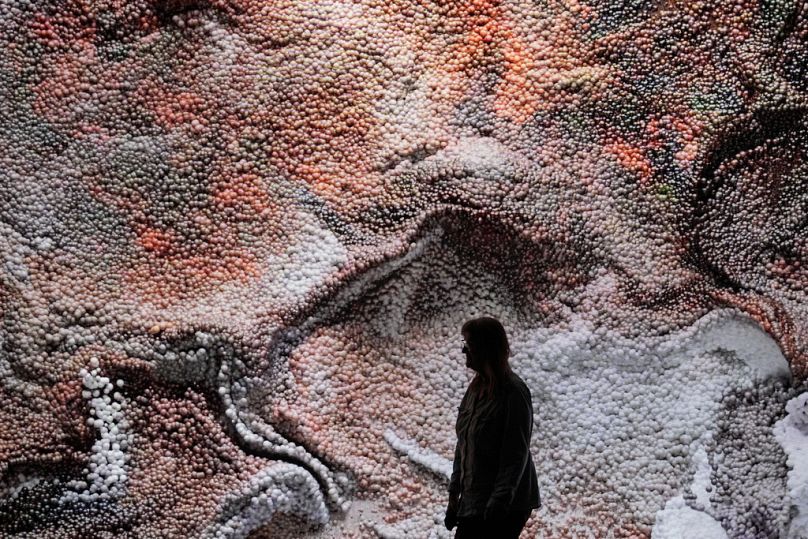 Visitors watch flowing data sculptures at the exhibition "Refik Anadol. Machine Hallucinations" at the Kunstpalast art museum in Duesseldorf, May 2023