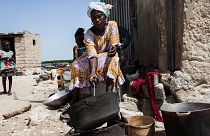 Uma mulher assa amendoins no exterior da sua casa na ilha de Diamniadio, no Senegal.