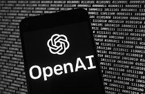 Das OpenAI-Logo erscheint auf einem Mobiltelefon vor einem Computerbildschirm mit binären Zufallsdaten, Donnerstag, 9. März 2023, in Boston.