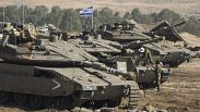 جنود إسرائيليون يتحركون فوق دبابة بالقرب من الحدود بين إسرائيل وغزة