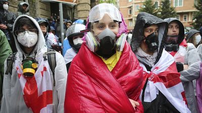 Manifestantes com máscaras de gás junto ao edifício do Parlamento durante um protesto da oposição contra "a lei russa" no centro de Tbilisi, Geórgia, na segunda-feira, 13 de maio de 2024