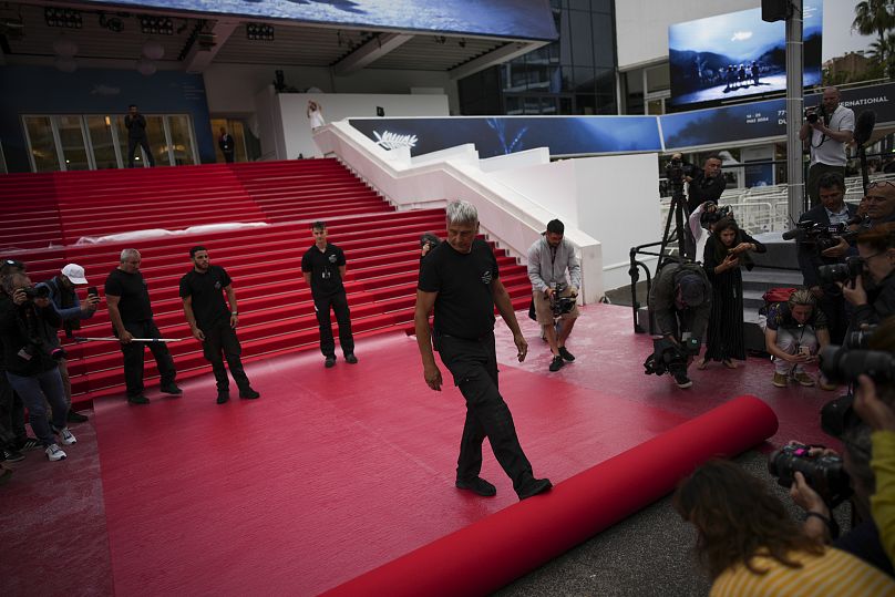 Техперсонал расстилает красную дорожку на лестнице Дворца фестивалей в день открытия 77-го кинофестиваля в Каннах, 14 мая 2024 г.