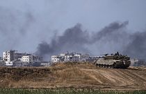 Gazze sınırında bulunan bir İsrail tankı ve kentin içinde bombardıman sonrası yükselen siyah dumanlar
