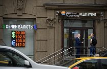 Two men talk to each other at the entrance of a currency exchange office in Moscow, Russia