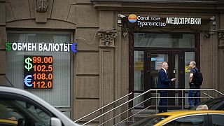 Two men talk to each other at the entrance of a currency exchange office in Moscow, Russia