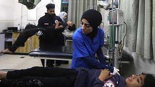 Médicos palestinianos tratam um ferido enquanto outro carrega um jovem ferido nos bombardeamentos israelitas na Faixa de Gaza, no Hospital Kuwaiti, no campo de refugiados de Rafah, 