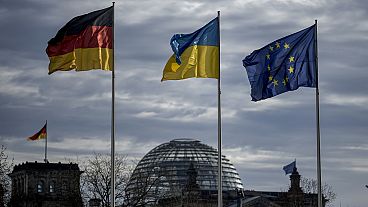 Μια γερμανική, ουκρανική και ευρωπαϊκή σημαία κυματίζουν μπροστά από το κτίριο του Ράιχσταγκ στο Βερολίνο, Γερμανία, Παρασκευή 16 Φεβρουαρίου 2024. 