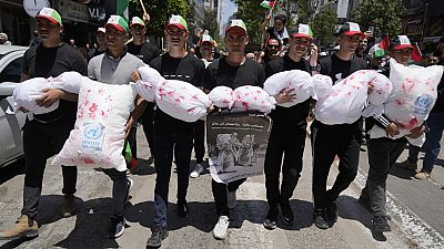 Palestinians carry bloodstained mock children bodies during a mass ceremony to commemorate the Nakba Day
