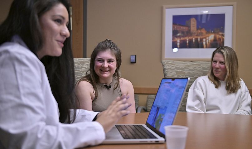 Alexis Bogan (centre) and her mother Pamela Bogan (right) react to hearing a recreation of her lost voice from a prompt typed by Dr Fatima Mirza (left).