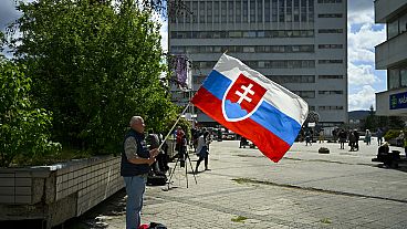 Un hombre reza sosteniendo la bandera de Eslovaquia frente al Hospital Universitario F. D. Roosevelt de Banská Bystrica, donde permanece ingresado Robert Fico.