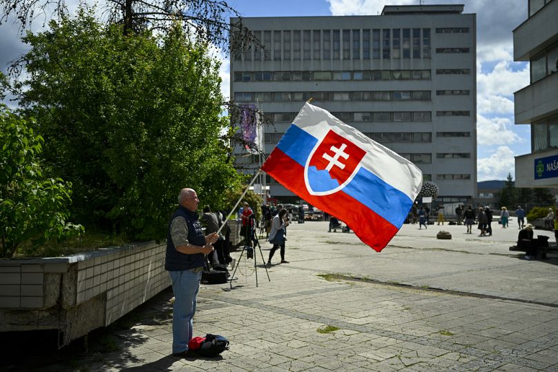 A man prays holding Slovakia's flag outside the F. D. Roosevelt University Hospital, Banska Bystrica, central Slovakia, Thursday, May 16, 2024.