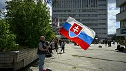 Un uomo prega tenendo in mano la bandiera slovacca fuori dall'ospedale F.D. Roosevelt, dove è ricoverato il primo ministro Robert Fico, Banska Bystrica, 16 maggio 2024